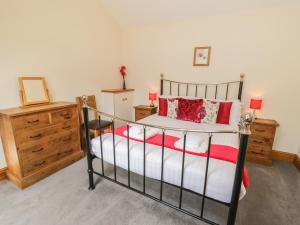 a bedroom with a metal bed with red and white pillows at Kitchen Cottage in Sutton