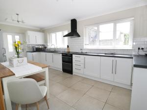 a kitchen with white cabinets and black appliances at Orchard Cottage in Holywell