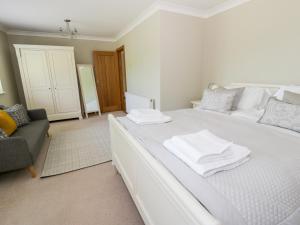 ein weißes Bett mit weißen Handtüchern darüber in der Unterkunft Orchard Cottage in Holywell