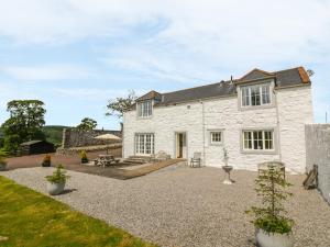 een wit stenen huis met een patio en een tuin bij Bracken Holiday Cottage in Dalbeattie
