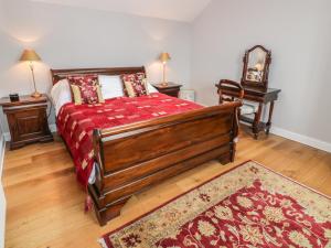 Un dormitorio con una cama grande con una manta roja. en Bracken Holiday Cottage, en Dalbeattie