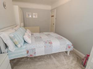 a bedroom with a bed with a quilt and pillows at Salee Cottage in Newbiggin-by-the-Sea
