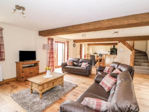 a living room with a leather couch and a table at Pentre Fawr in Llanddewi Ystradenny