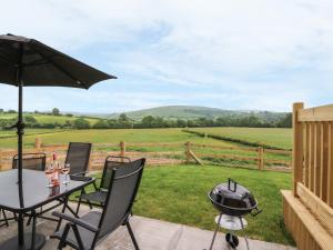 a patio with a grill and a table and chairs at Pentre Fawr in Llanddewi Ystradenny