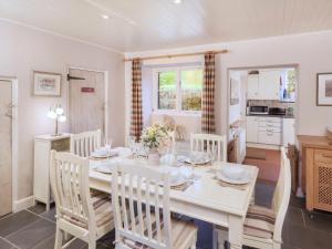 una cucina e una sala da pranzo con tavolo e sedie bianchi di 2 Bittadon Cottages a Barnstaple