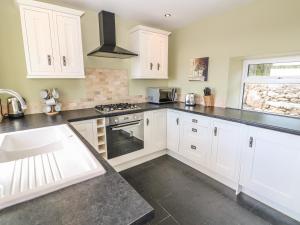 a kitchen with white cabinets and black counter tops at Bryn Uchaf in Benllech