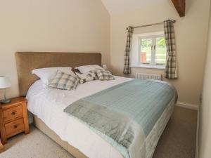 a bedroom with a bed with pillows and a window at Lake Farm Cottage in Ripon