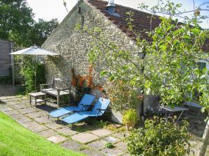 a patio with two chairs and a bench and an umbrella at Acorn Cottage in Bruton