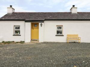 a white building with a yellow door and a bench at Mary Larkin's Cottage in Lisnacree