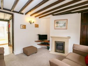 a living room with a fireplace and a tv at Japonica Cottage in Bourton on the Water