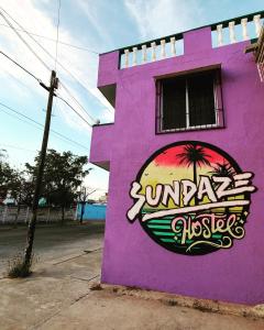 a purple building with a palm tree painted on it at Sundaze Homestay in Mazatlán