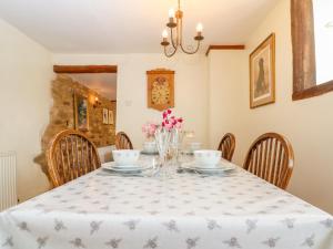 uma sala de jantar com uma mesa com cadeiras e flores em Henmarsh Cottage em Moreton-in-Marsh