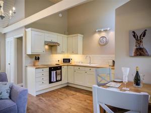 a kitchen with white cabinets and a table and a dining room at Lime Tree in Burford