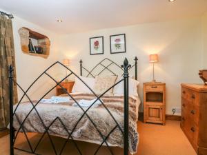 um quarto com uma cama preta e uma cómoda em Henmarsh Cottage em Moreton-in-Marsh