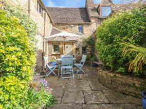 a patio with a table and chairs and an umbrella at Bull Cottage in Burford