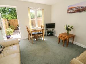 a living room with a table and a television at Bramble Cottage in Sedbergh
