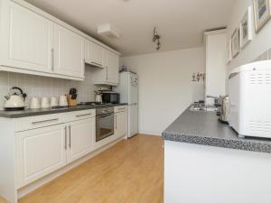 a kitchen with white cabinets and a counter top at Strawberry Cottage in Penryn