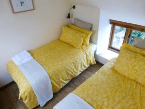 a bedroom with two beds with yellow sheets and a window at The Old Cottage in Weston-super-Mare