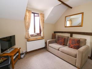 a living room with a couch and a tv at Oak Cottage in Llanidloes