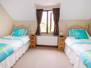 two twin beds in a room with a window at Cedar Cottage in Llanidloes
