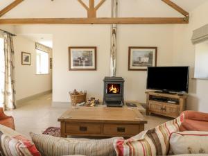 a living room with a fireplace and a tv at Cow Byre in Great Habton