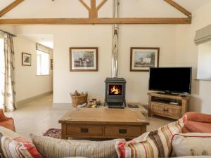 sala de estar con chimenea y TV en Cow Byre en Great Habton