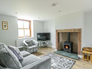 a living room with a couch and a fireplace at 1 Leesrigg Cottages in Wigton
