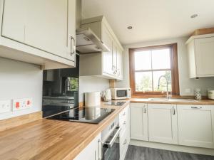 a kitchen with white cabinets and a window at 1 Leesrigg Cottages in Wigton