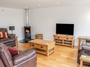 a living room with a couch and a tv and a fireplace at The Cow Byre, Heath Farm in Clee Saint Margaret