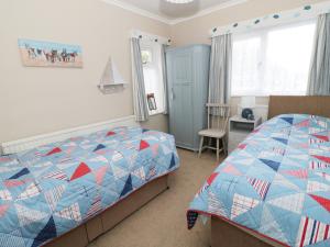1 dormitorio con 1 cama con edredón azul y rojo en Salty Puffin, en Benllech