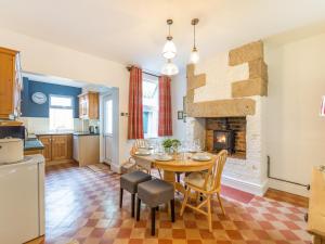 a kitchen and dining room with a table and a fireplace at Bobbin Cottage in Matlock