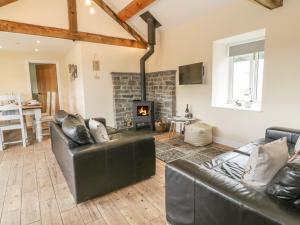 a living room with leather furniture and a fireplace at Rhianwen, Plas Moelfre Hall Barns in Llangadwaladr