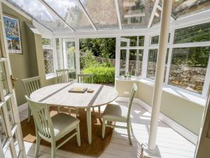 a conservatory with a table and chairs and windows at Blenheim Edge, The Causeway in Woodstock