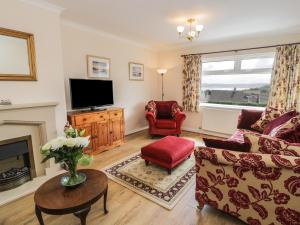 a living room with a couch and a tv at Bay View in Benllech