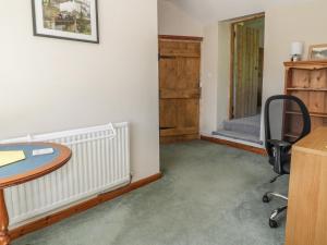 ein Büro mit einem Schreibtisch, einem Stuhl und einem Tisch in der Unterkunft The Cottage in Llangollen