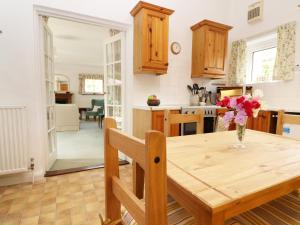 uma cozinha com uma mesa de madeira e um vaso de flores em Westgate Cottage em Sittingbourne