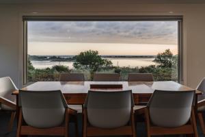 una sala de conferencias con mesa, sillas y una gran ventana en Umtali Beach House, en Bridport