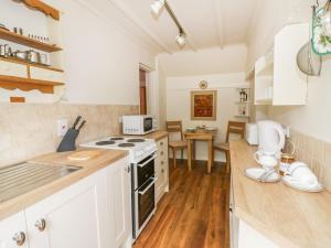 eine Küche mit weißen Schränken und einem Herd mit Backofen in der Unterkunft The Cottage in Pershore + 11 Fotos