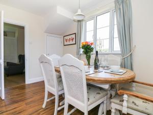 ein Esszimmer mit einem Tisch, Stühlen und einem Fenster in der Unterkunft New Park Farm Cottage in Brockenhurst