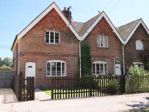 a brick house with a wooden fence in front of it at New Park Farm Cottage in Brockenhurst