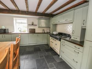 uma cozinha com armários brancos e uma mesa de madeira em Plas Mawr em Caernarfon