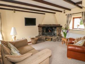 sala de estar con sofá y chimenea en The Cottage, en Calton