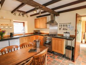 a kitchen with wooden cabinets and a wooden table at The Cottage in Calton +11 photos