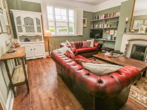 a living room with a leather couch and a fireplace at Londesborough Cottage in Scarborough