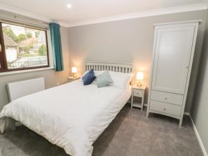 een slaapkamer met een wit bed en een raam bij 3 Trem Afon in Colwyn Bay