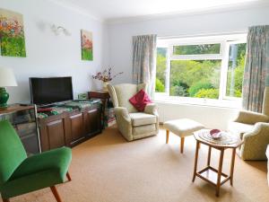 a living room with a tv and chairs and a window at Swn Y Coed in Corwen