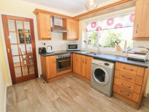 a kitchen with a washing machine and a window at Trem Y Garn in Pwllheli