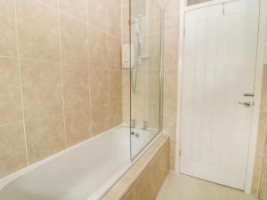 a bathroom with a tub and a glass shower door at Trem Y Garn in Pwllheli +4 photos