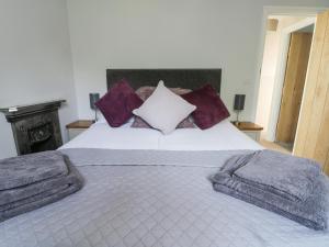 a bedroom with a large white bed with purple pillows at Corner View in Great Driffield