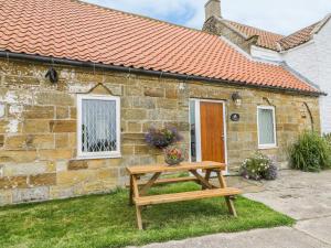 a wooden picnic table in front of a stone house at Milton Cottage in Whitby